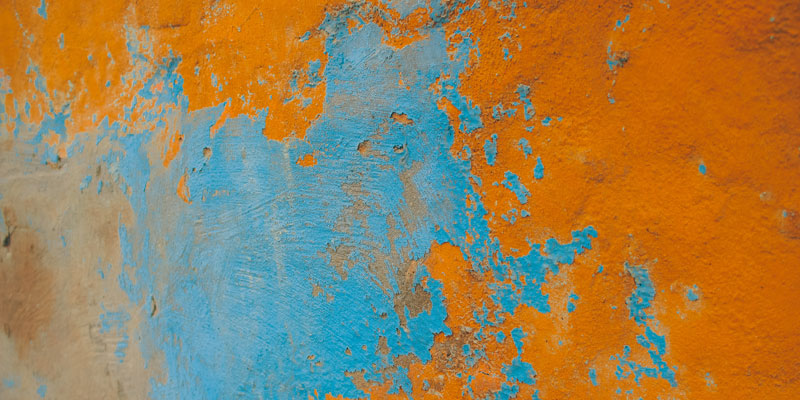 peeling layers of blue and orange paint on wall