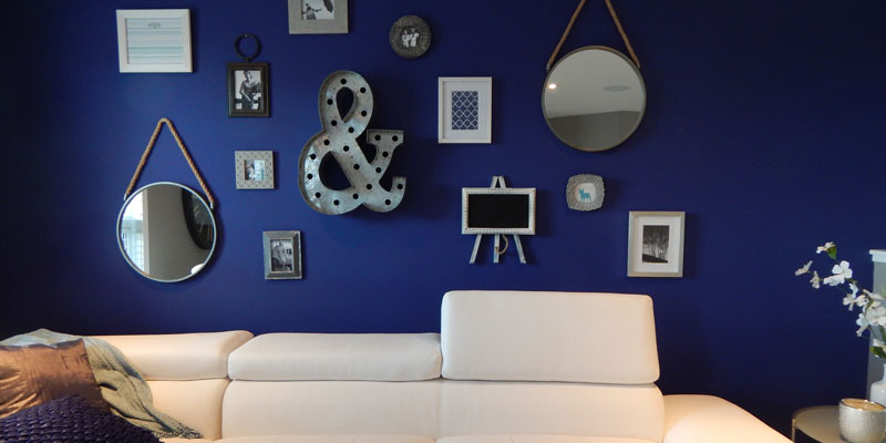 white sofa against boldly blue-painted wall with many wall decorations