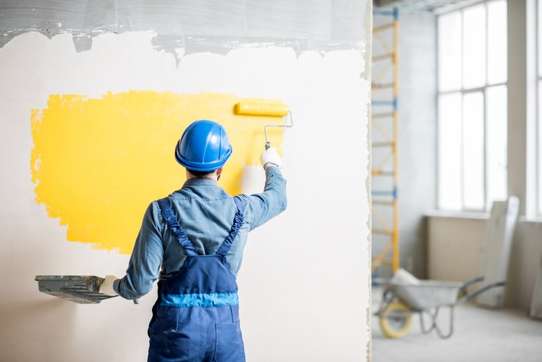 major painting employee painting newly constructed wall in office remodel