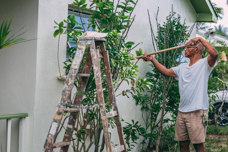 man painting the exterior of his house