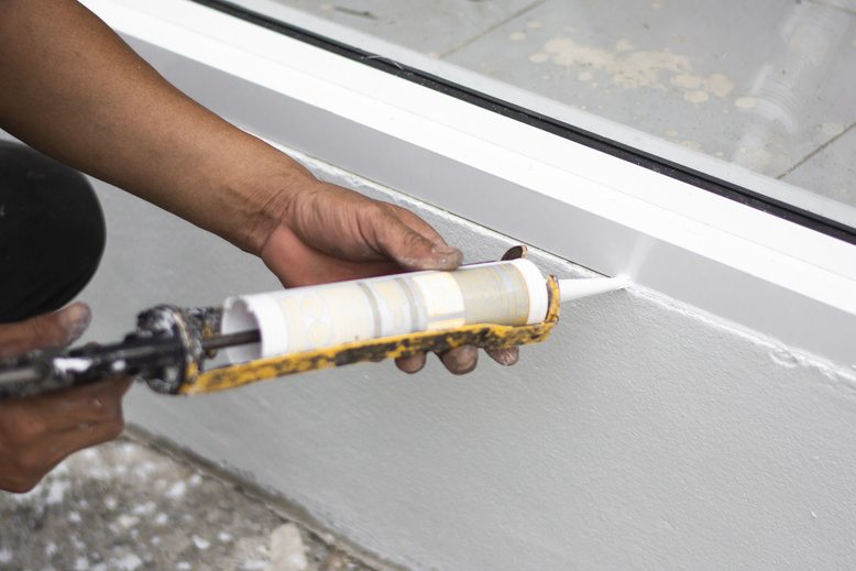 professional painter caulking outside of commercial building