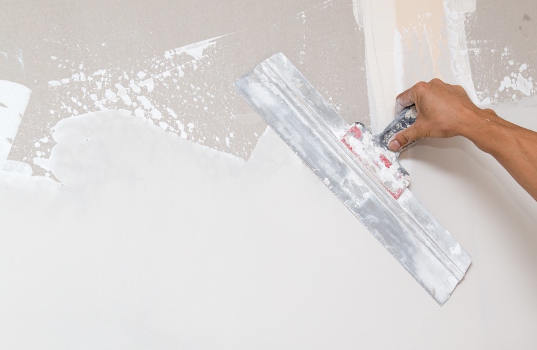 professional painter repairing damaged drywall in commercial building