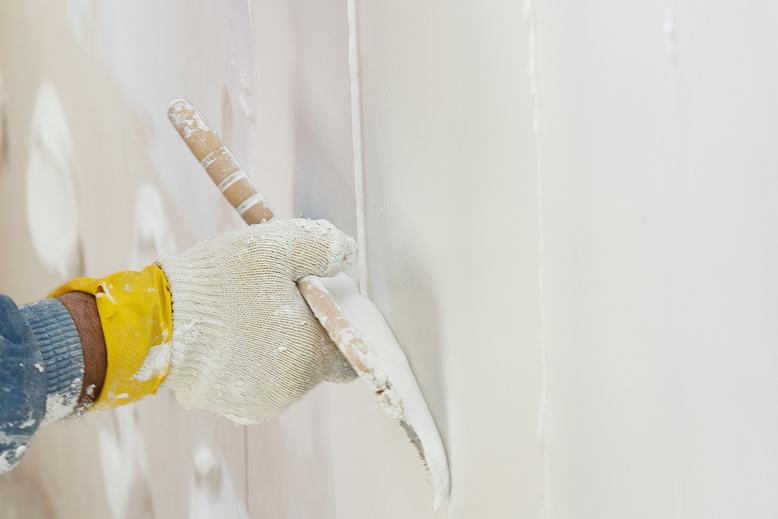 professional painter repairing damaged drywall to prepare for painting