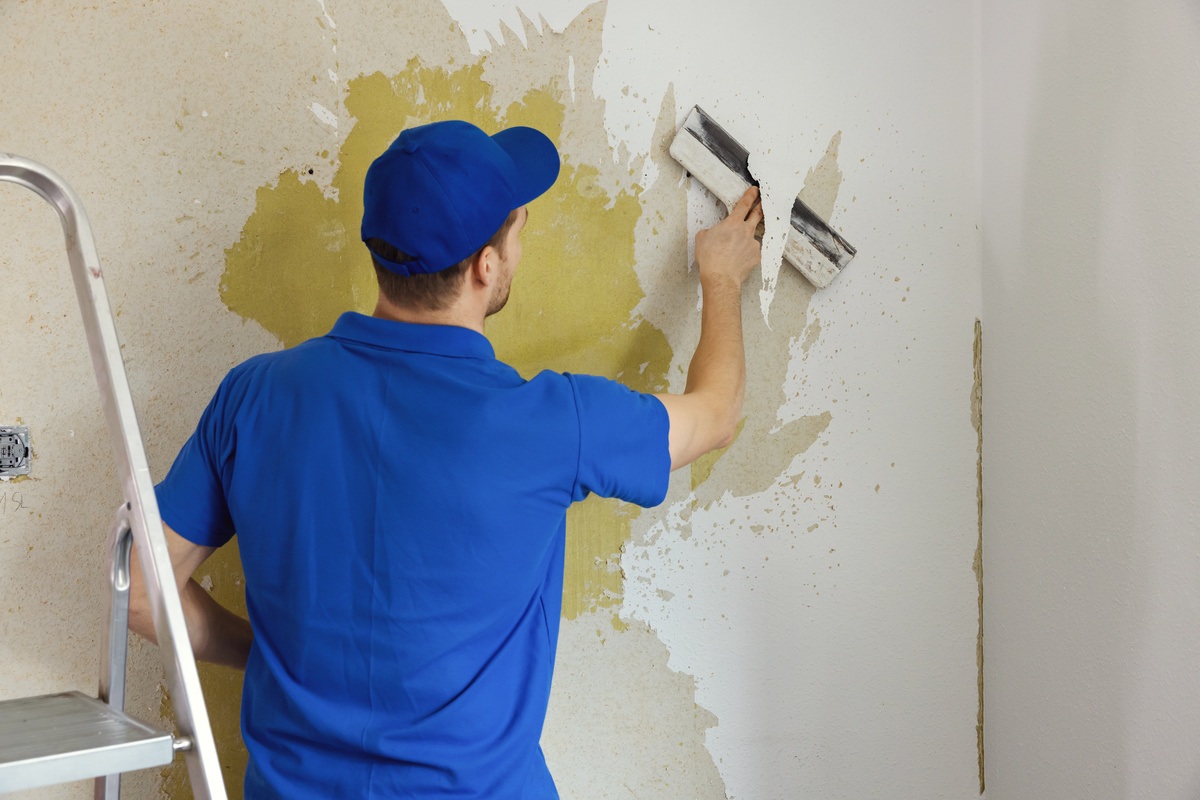 commercial painter removing wallpaper in commercial building