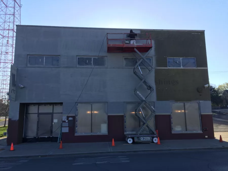 professional painter applying base coat of paint on retail building